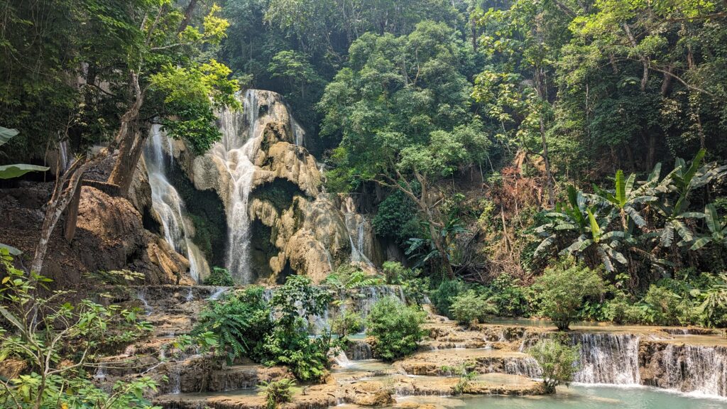 cascading waterfall in the backdrop with small waterfalls in the foreground